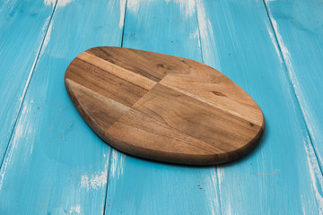 Oval cutting board on blue wooden background with perspective