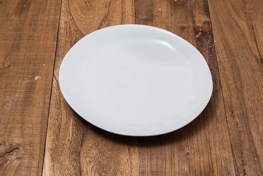 White Plate on brown wooden background side view