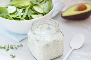Obraz na płótnie Canvas Yogurt mustard dressing to green spinach avocado salad