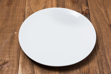 White Plate on brown wooden background side view