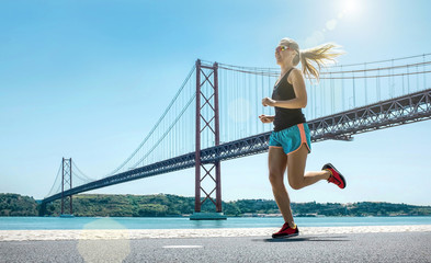 Blonde woman running training on the coastline near the Bridge u