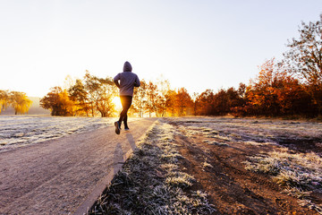 Man jogging outdoors, working out on sunny autumn morning