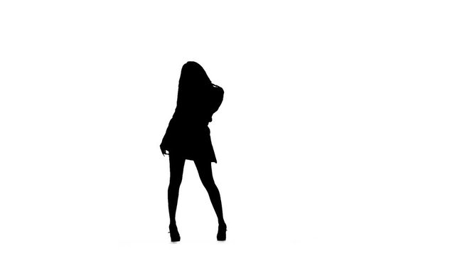 Woman is dancing a sexy dance. Silhouette. White background. Slow motion