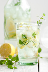 Citrus lemonade in a glass cup on a white wooden table close-up..