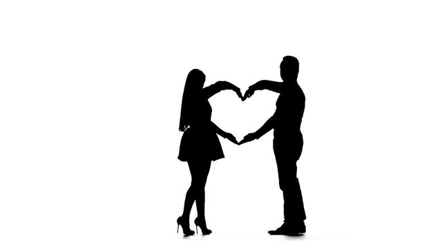 Loving couple makes a heart shape with the help of hands. Silhouette. White background. Slow motion