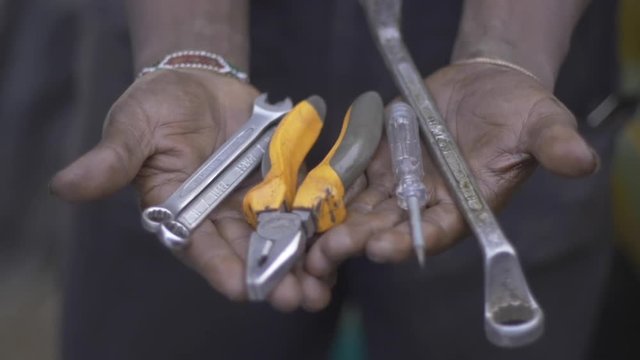 African mechanic holds tools portrait, close up.