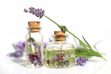 Obraz na płótnie Canvas Lavender oil. Oil with lavender flower in a glass bottle and sprigs of lavender on a white background. Botanical cosmetics concept