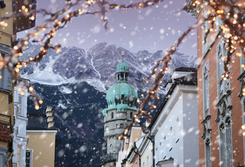 Roofs of Innsbruck with mountains on a background and Christmas lights on a foreground at winter snowy evening - obrazy, fototapety, plakaty