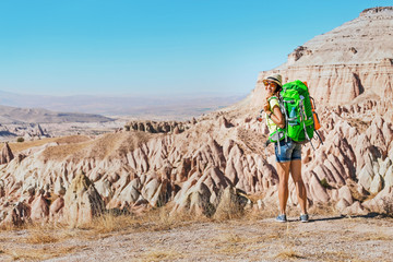 Young happy active tourist woman with backpack travel and trekking at Cappadocian deserted canyons and valleys, Turkey.