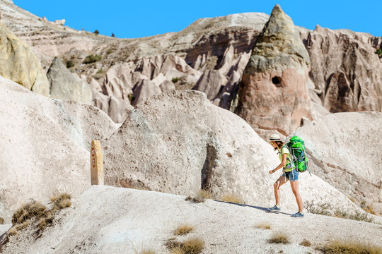 Young happy active tourist woman with backpack travel and trekking at Cappadocian deserted canyons and valleys, Turkey.