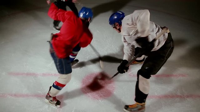 hockey referee produces a faceoff and the two players begin to fight for the puck