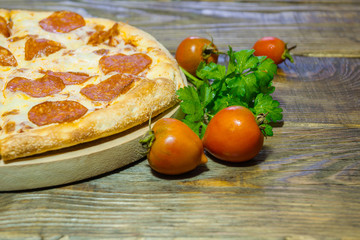 Italian Pepperoni pizza with salami on dark wooden background. Italian traditional food. A textured background. Copy paste place
