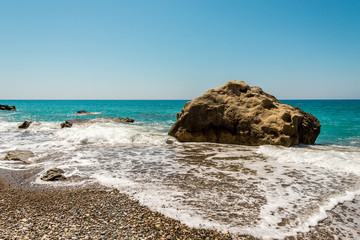 A large rock surrounded by water at Pissouri pebble beach, Cyprus