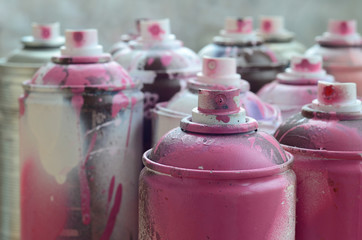 A lot of dirty and used aerosol cans of bright pink paint. Macro photograph with shallow depth of...