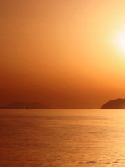 Naklejka na ściany i meble Coucher de soleil depuis la côte, mer, îles