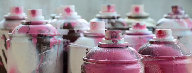 A lot of dirty and used aerosol cans of bright pink paint. Macro photograph with shallow depth of...