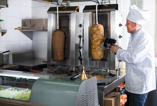 mature chef slicing kebab in fast food.