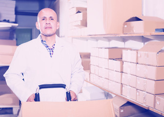 Worker performing loading works in storage © JackF