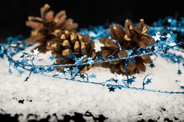 Three pine cone on snow with blue star thread. Christmas decoration.