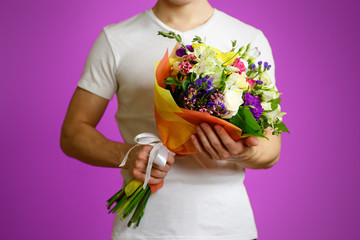 Young guy in a white shirt holding a beautiful bouquet of flowers. Isolated