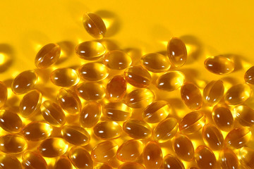 Omega-3 fish fat oil capsules on a yellow background