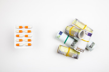 Different medications and pills with euro banknotes on a white background