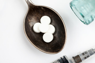 Medications and pills with spoon and syringe on a white background