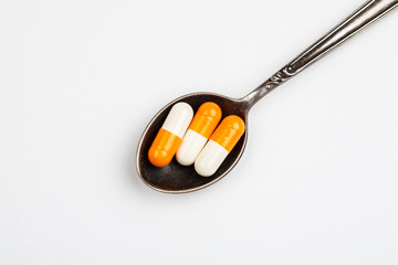 Medications in a metal spoon on a white background
