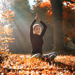 A young woman make yoga position at sunrise. in the autumn forest.
