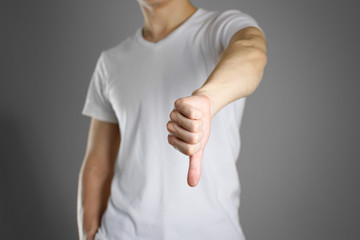 Man in blank white t-shirt shows thumb down. Isolated