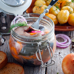 Swedish traditional marinated herring with onions and carrots in a glass jar, selective focus