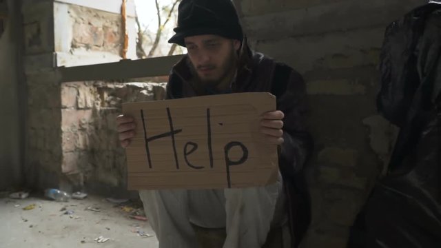Hungry ill homeless with cardboard "help"