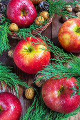 Red apples, fir branches, walnuts, chestnuts and cones on a wooden background, christmas concept, harvest, holiday and new year
