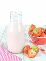 A bottle of strawberry yogurt milkshakes on a wooden table with fresh fruit and copy space