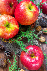 Red apples, fir branches, walnuts, chestnuts and cones on a wooden background, christmas concept, harvest, holiday and new year