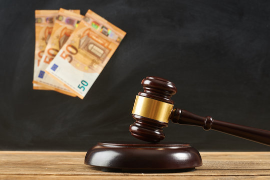 Judge gavel on wooden table at blackboard background with money.