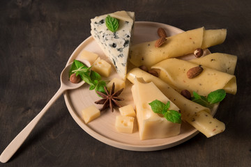 white mould cheese. sliced yellow cheese on wooden plate standing on dark wooden table