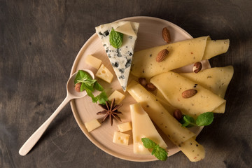 white mould cheese. sliced yellow cheese on wooden plate standing on dark wooden table