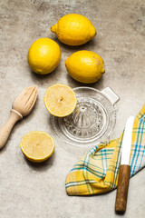 Limones y exprimidor, cuchillo y servilleta sobre mesa gris rústica. Vista superior.