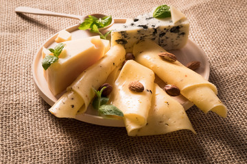 white mould cheese sliced yellow cheese on wooden plate stand on an old flax tablecloth