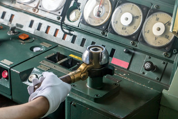 Hand in white gloves of Japanese rail driver check joystick in cab of locomotive. Controll train from the driver's cab, close up.