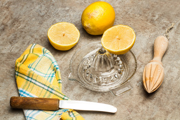 Limones y exprimidor, cuchillo, servilleta sobre mesa gris rústica. Vista superior.