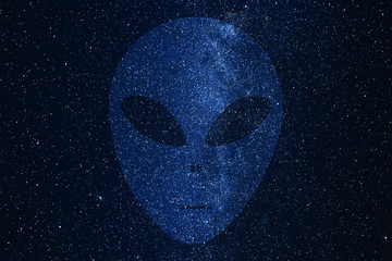 Alien face silhouette on background of Milky Way galaxy with glowing stars and planets in the...