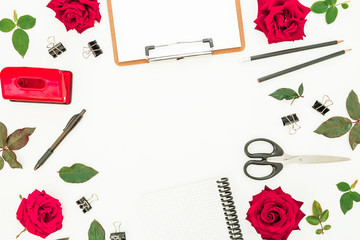 Feminine desk workspace with clipboard, notebook, accessories and red flowers on white background. Flat lay, top view.