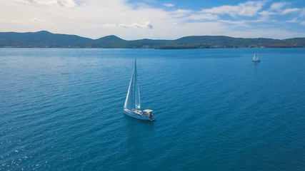 Obraz na płótnie Canvas Aerial view of yacht sailing near beautiful Islands. Beautiful clouds in the background. Luxury yacht in the sea.