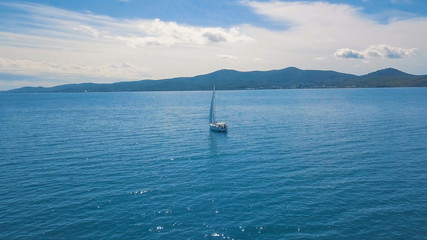 Aerial view of yacht sailing near beautiful Islands. Beautiful clouds in the background. Luxury yacht in the sea.