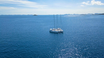 Fototapeta premium Aerial view of yacht sailing near beautiful Islands. Beautiful clouds in the background. Luxury yacht in the sea.