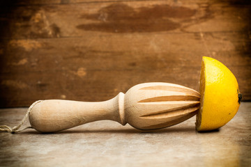 Exprimidor de madera junto a un limón cortado por la mitad sobre una mesa. Vista de frente. Copy...