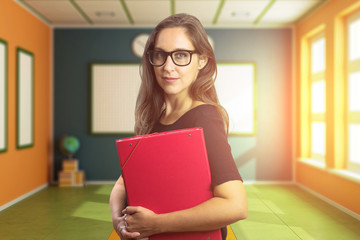 Beautiful teacher or blonde student holding material inside the classroom