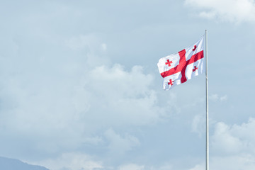 Flag of Georgia on the flagstaff. Sky and clouds on the background